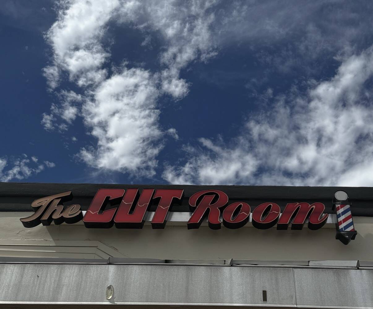 The Cut Room storefront sign and barber pole beneath the Arizona sky